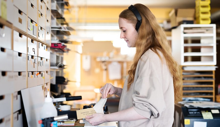 Mitarbeiterin bearbeitet gravierte Messingschilder für eine Bestellung